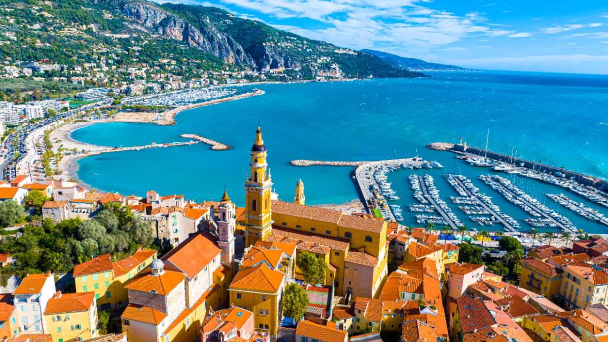 Menton - Luftaufnahme über die Stadt und den Hafen mit den Bergen im Hintergrund bei Reisemagazin Plus